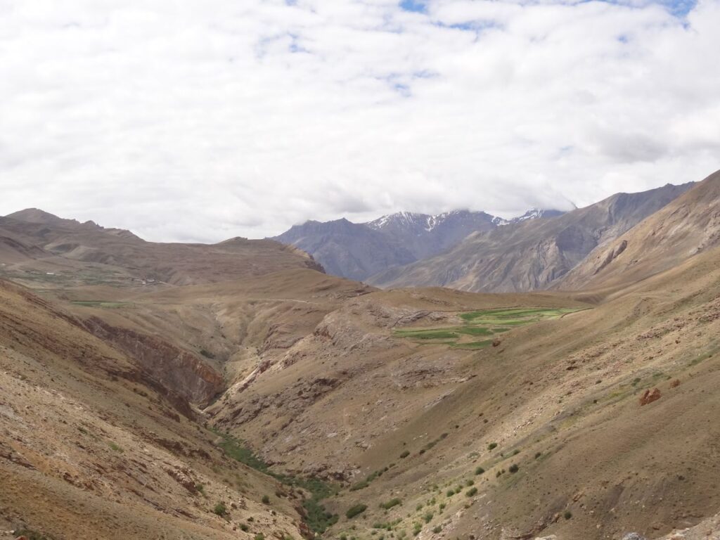Distant view of Dumla village and green fields separated by a gorge